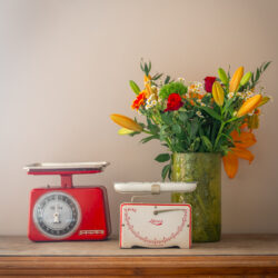 Foto van een decoratief tafereel met boeket bloemen en 2 vintage weegschalen